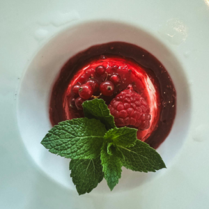 A delectable red berry dessert garnished with fresh mint leaves, captured in a Berlin cafe.