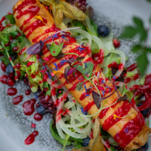 Elegant gourmet dish with a colorful salad and berry sauce drizzle, perfect for fine dining.