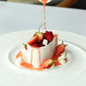 Indulge in a gourmet dessert with fresh strawberries and silky sauce in a French restaurant.